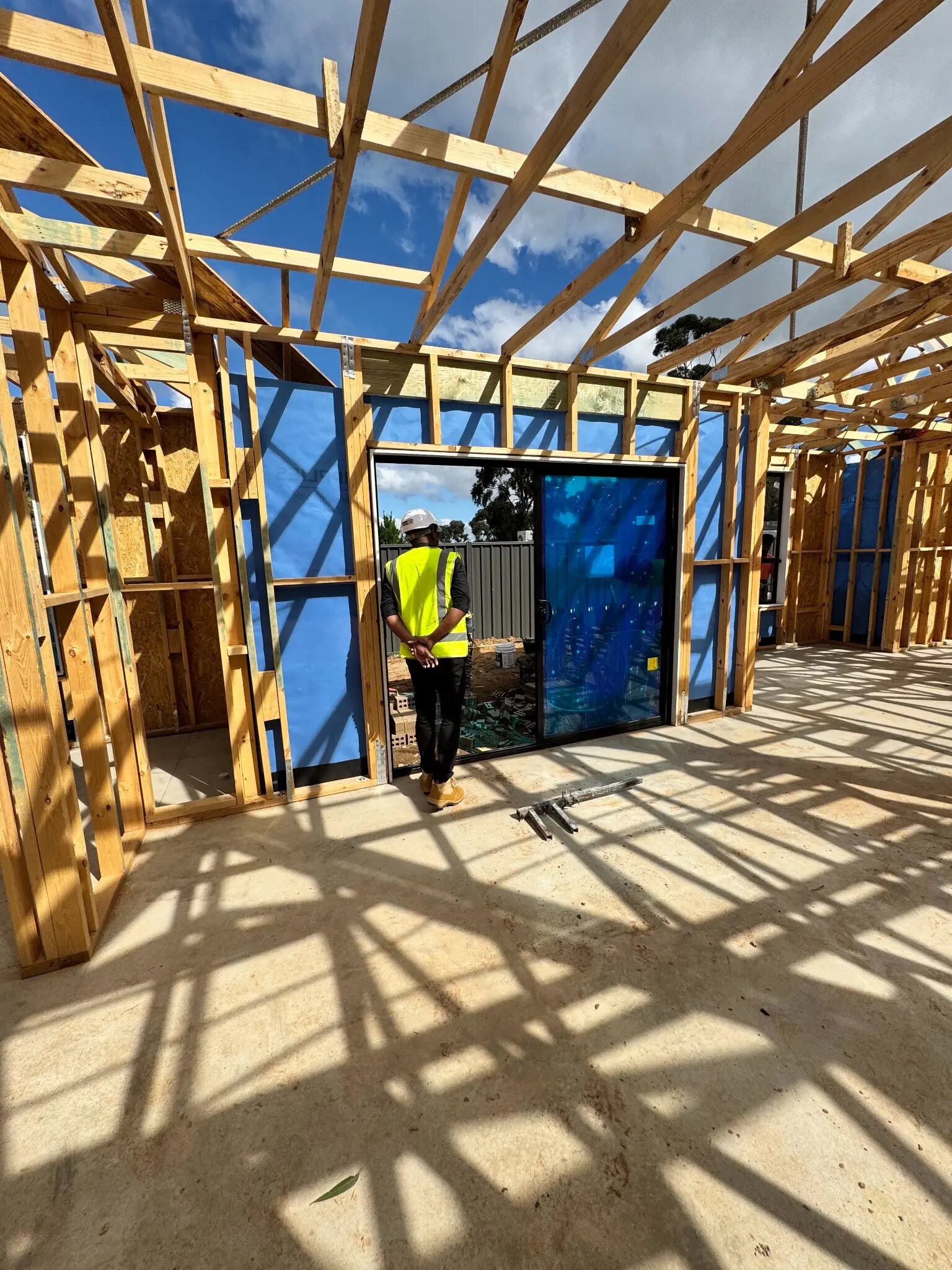Site supervisor reviewing timber framing and a large glazed opening