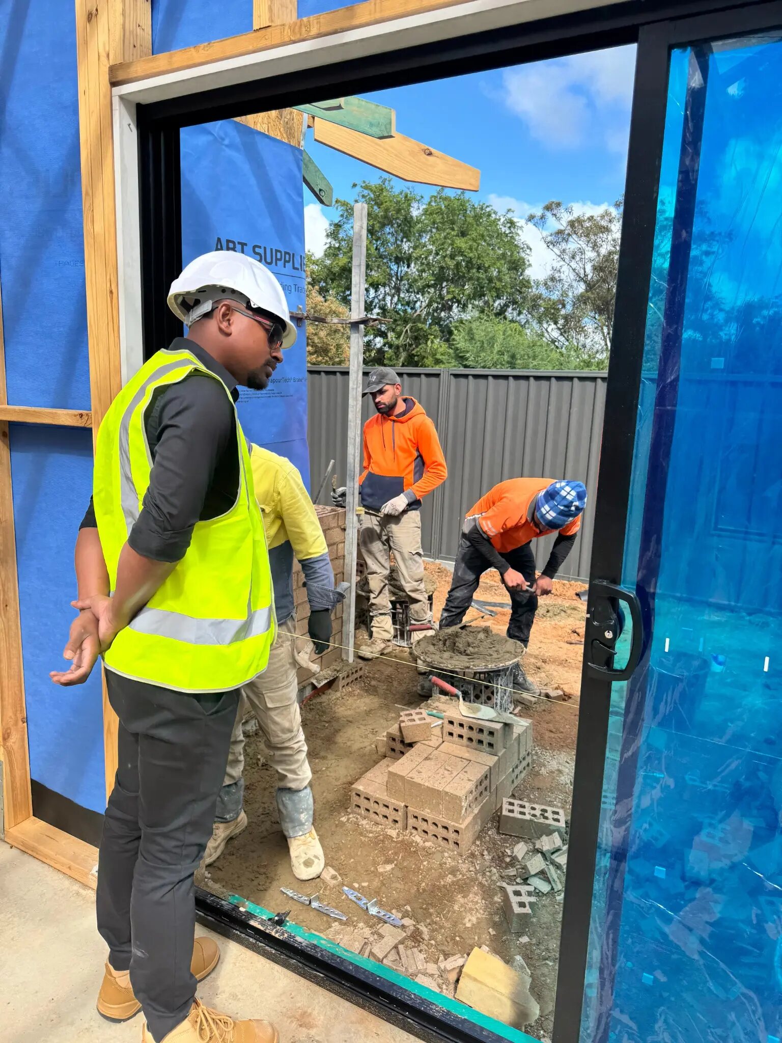 Imon Hussain coordinating brickwork beside a large glazed opening