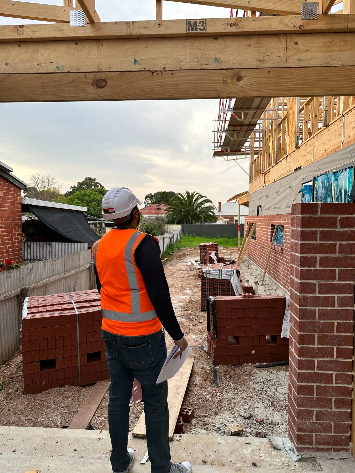 Imon Hussain walking through brickwork and framing progress on a residential build