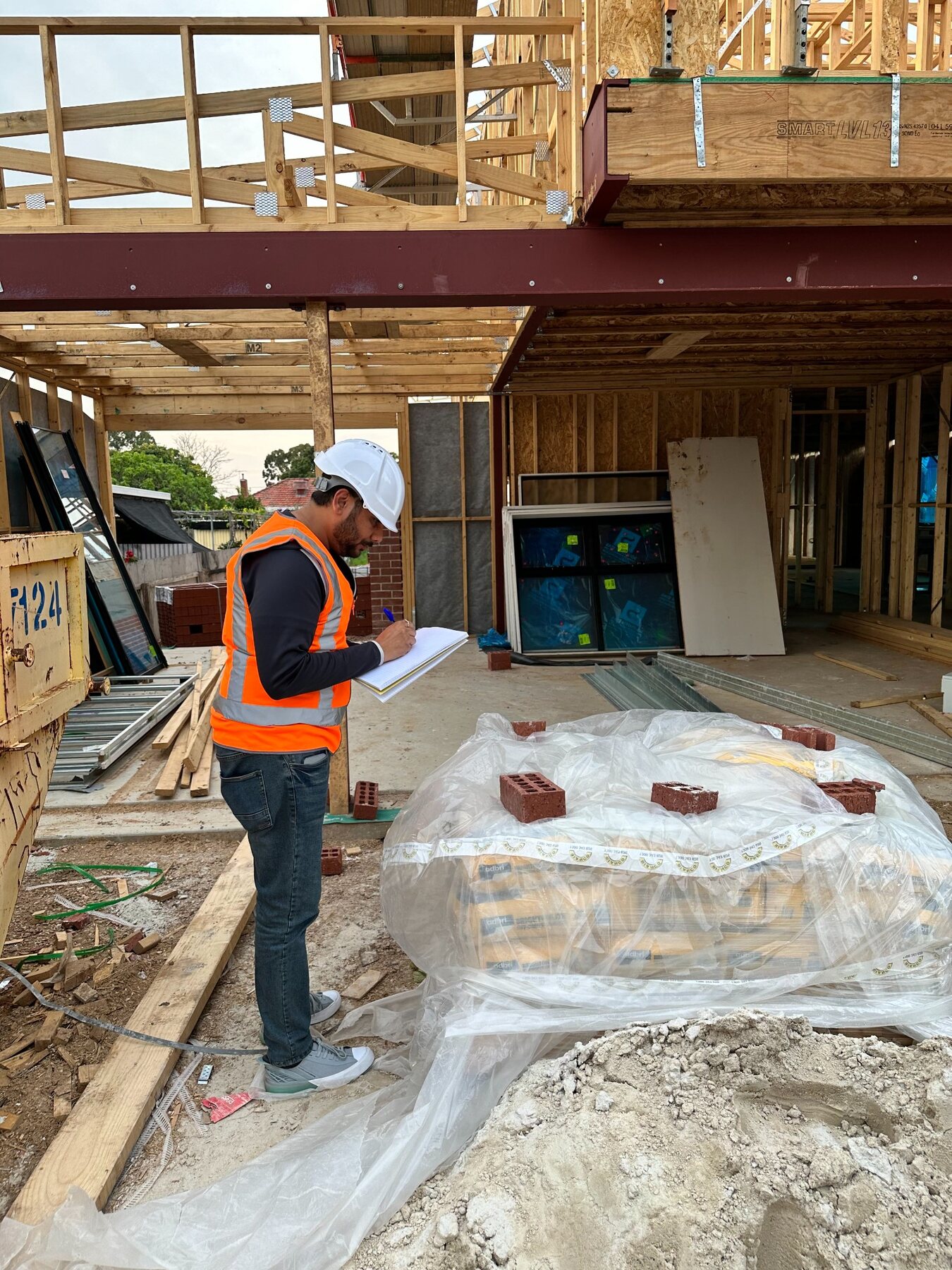 Imon Hussain writing notes while inspecting framing and materials on site