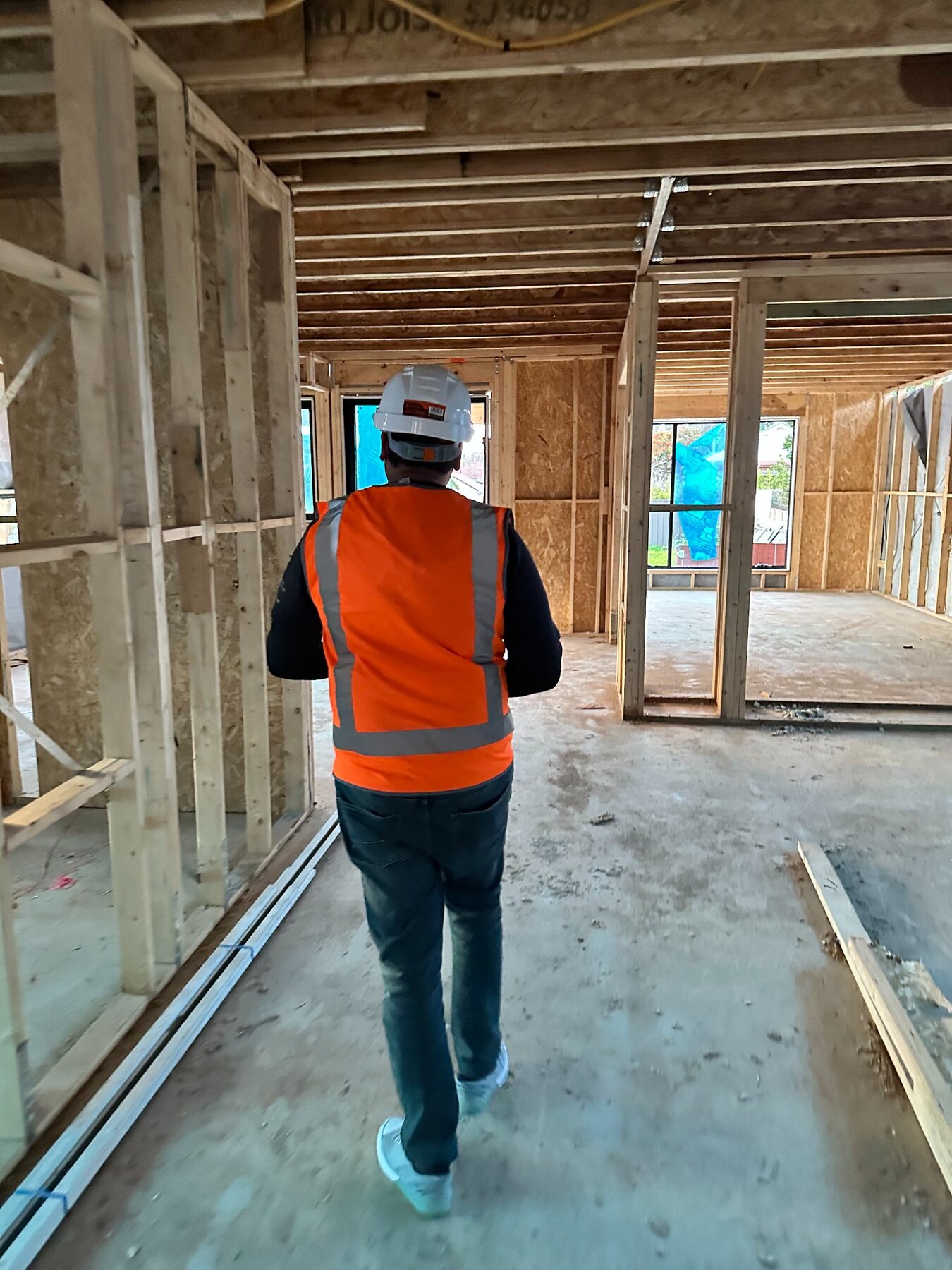 Imon Hussain walking through interior framing on a residential construction site