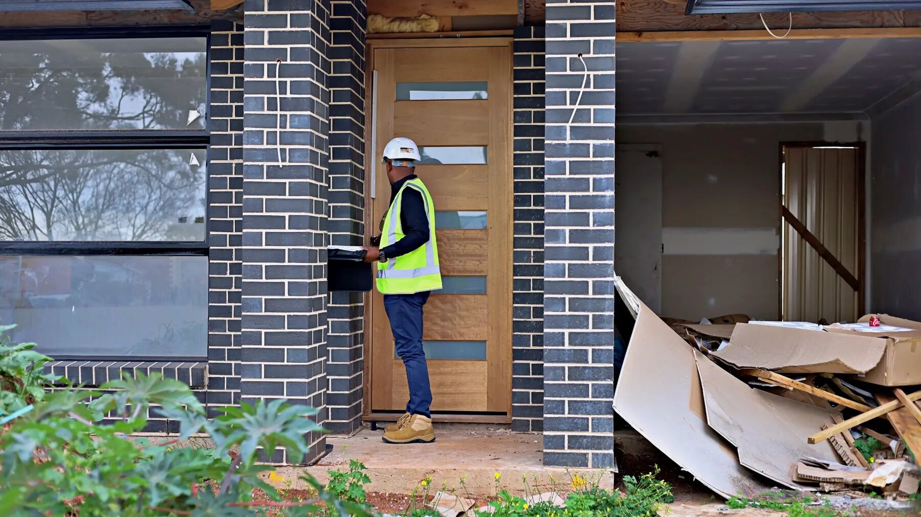 Imon Hussain reviewing the front entry of a contemporary brick home