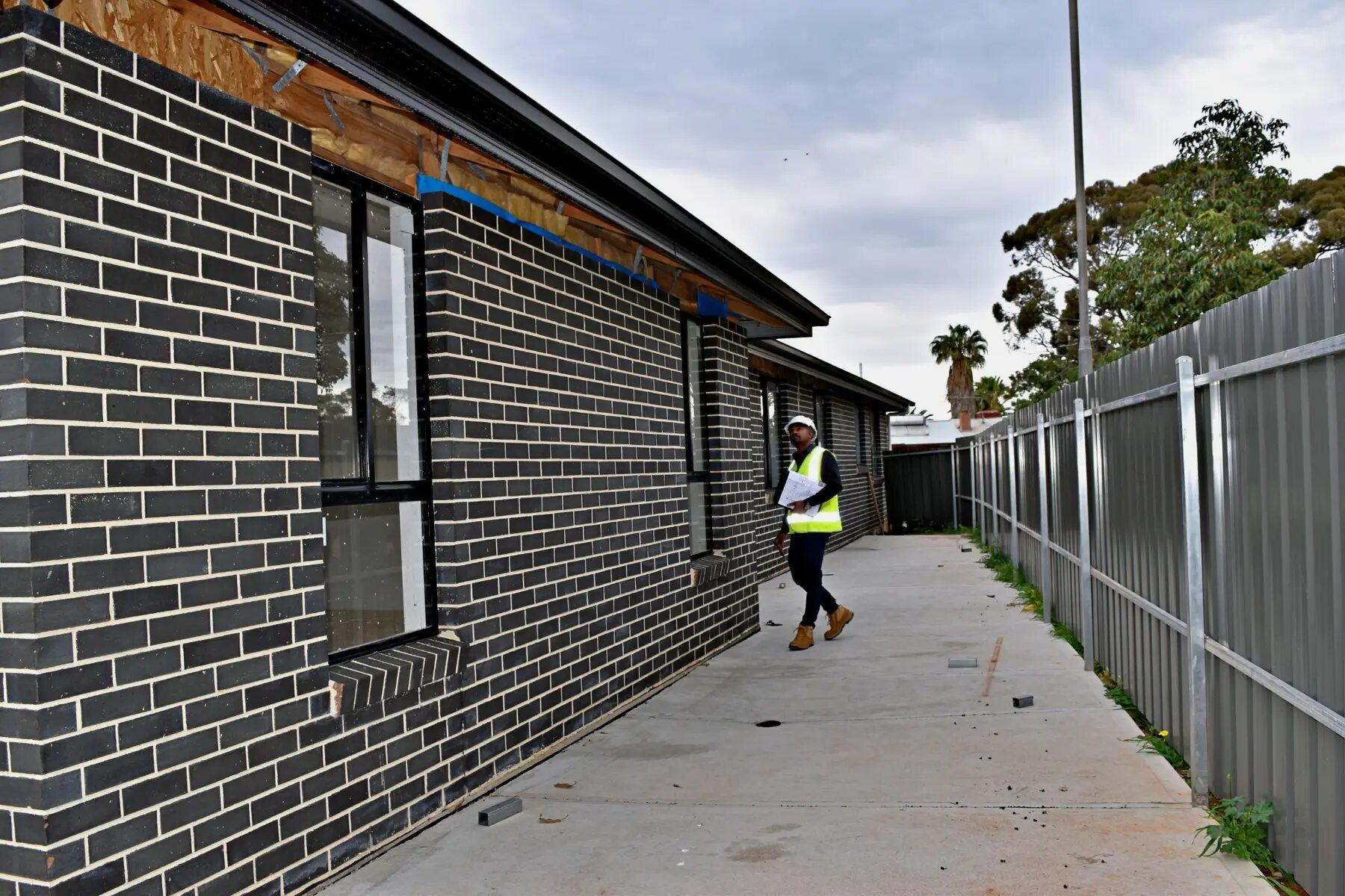 Imon Hussain inspecting the exterior of a contemporary brick residence